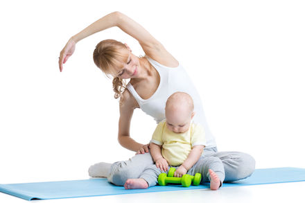 A woman stretches while her baby plays nearby